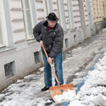 man shoveling snow out of his property