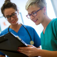 two nurses talking to each other with clipboard