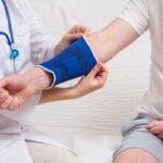 doctor helps the patient to use bandage on the elbow