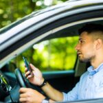 Man driving and looking message in his smart phone.