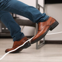 Man tripping over cord in office, closeup