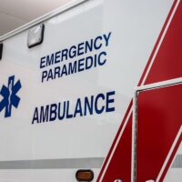 Paramedic Emergency ambulance logo on side of truck with red stripes and blue cross