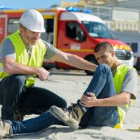 injured lying worker at work being assisted