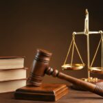 Gavel with books and scales on brown background Gavel with books and scales on brown background