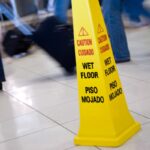 Picture of a Caution Wet Floor yellow cone sign with blurred motion people walking in the background Picture of a Caution Wet Floor yellow cone sign with blurred motion people walking in the background