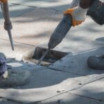 Two workers are using a jackhammer to fix damaged pavement on a street. Two workers are using a jackhammer to fix damaged pavement on a street.