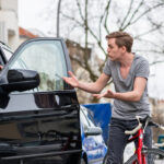 Angry young bicyclist shouting while swerving for avoiding dangerous collision with the open door of a 4x4 car on a busy street in the city