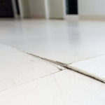 Ceramic tiles floor cracked and broken from concrete inflate in house or office building. Floor cracked in house problem renovation and repair concept.
