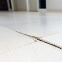 Ceramic tiles floor cracked and broken from concrete inflate in house or office building. Floor cracked in house problem renovation and repair concept. Ceramic tiles floor cracked and broken from concrete inflate in house or office building. Floor cracked in house problem renovation and repair concept.