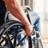 Man, hands and wheelchair for support, hope or travel in healthcare or medicare at home. Closeup of male or person with a disability moving on chair for mobility, surgery or wellness in the house.