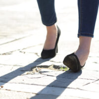 Close up of a woman legs with high heels spraining ankle while walking in the street