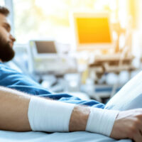 Young Man in Hospital Bed with Bandaged Arm and Medical Equipment