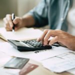 Deduction planning, debt asian accountant hand using calculator to calculating money balance from bill and income, cost budget expenses for pay money form personal individual on table at home. See Less