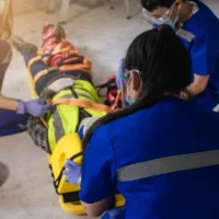 Paramedic woman and team first aid builder accident in site work. Team EMS paramedic first aid for head injuries. Employee accident in construction site work. Emergency service. First aid procedure.