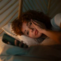 woman-suffering-insomnia-and-anxiety-scrolling-phone-in-bed